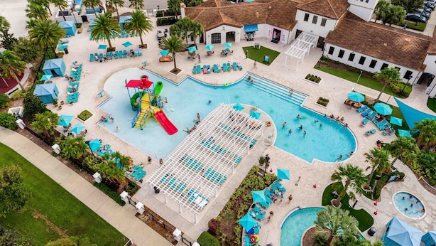 An aerial view of a resort with multiple swimming pools, sun loungers, and palm trees. - Huge Amazing Arcade Pool Home (Kissimmee)