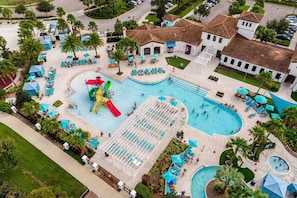 An aerial view of a resort with multiple swimming pools, sun loungers, and palm trees.