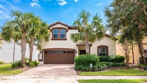 A two-story house with a brown garage door, palm trees, and a well-maintained lawn. - Huge Amazing Arcade Pool Home (Kissimmee)