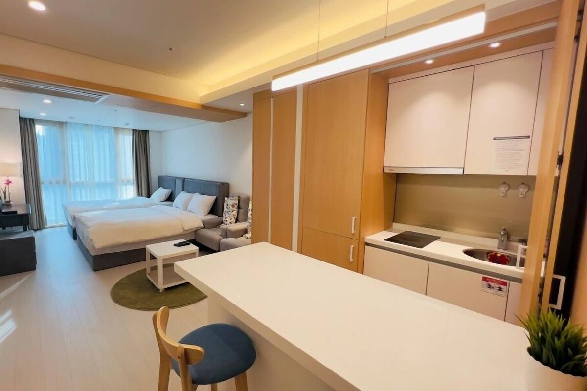 Una habitación de hotel moderna con una cama grande, un escritorio pequeño, una kitchenette y un televisor.