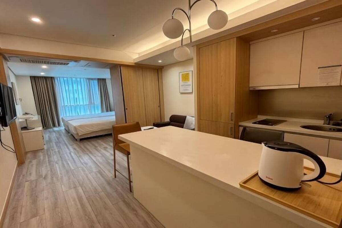 Habitación de hotel con kitchenette, cama, zona de estar y vistas al exterior.