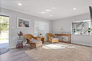 A room with a large window, wicker chairs, a small table, and a decorative vase.