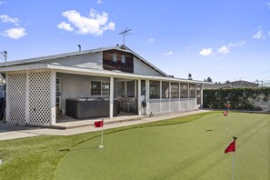 A covered outdoor area with a hot tub, seating, and a view of a golf course.
