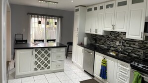 A modern kitchen with white cabinets, a black countertop, and a tiled backsplash. - Spacious 4 Bdrm House in Brampton (Brampton)