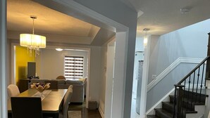 A spacious living area with a dining table, sofa, and staircase. - Spacious 4 Bdrm House in Brampton (Brampton)