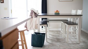 Une cuisine moderne avec une table à manger, des chaises et un sac posé sur le sol.