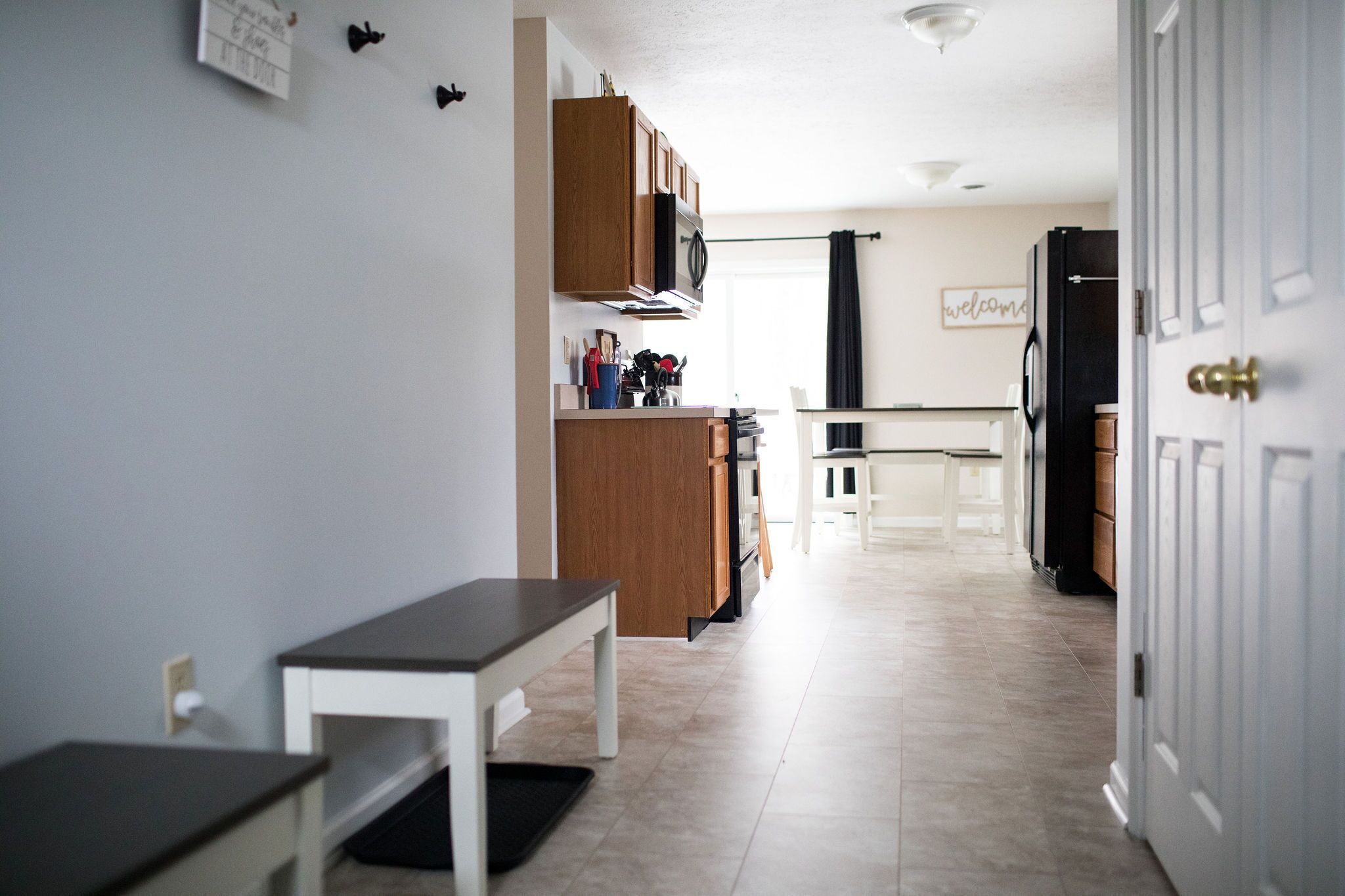 A modern kitchen with wooden cabinets, a microwave, and a dining area with a bench.