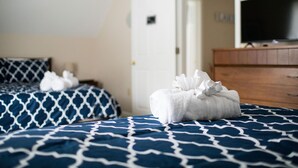 Une chambre d’hôtel avec deux lits, une commode en bois et un téléviseur posé sur un meuble.