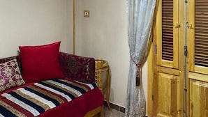 Un dormitorio con cama, armario, aire acondicionado y una lámpara decorativa.