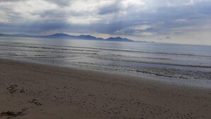 A beach with a wide sandy shore and calm water. - Min yr Afon - Cabin - Sleeps 2 - Hot Tub - Parking (Anglesey)