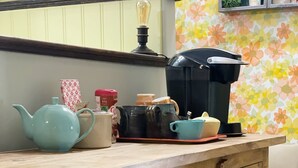 En køkkenbordplade med kaffemaskine, tepotte og kopper.