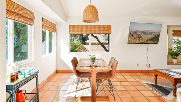 A dining area with a wooden table, chairs, and a hanging pendant light. - Foothills Southwest Sanctuary w/ Pool & Views (Tucson)