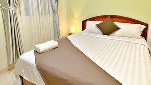 A neatly made bed with a brown bedspread and white linens, a wooden headboard, and a single white pillow. - S79 Boutique Hotel by hostify (Ho Chi Minh City)
