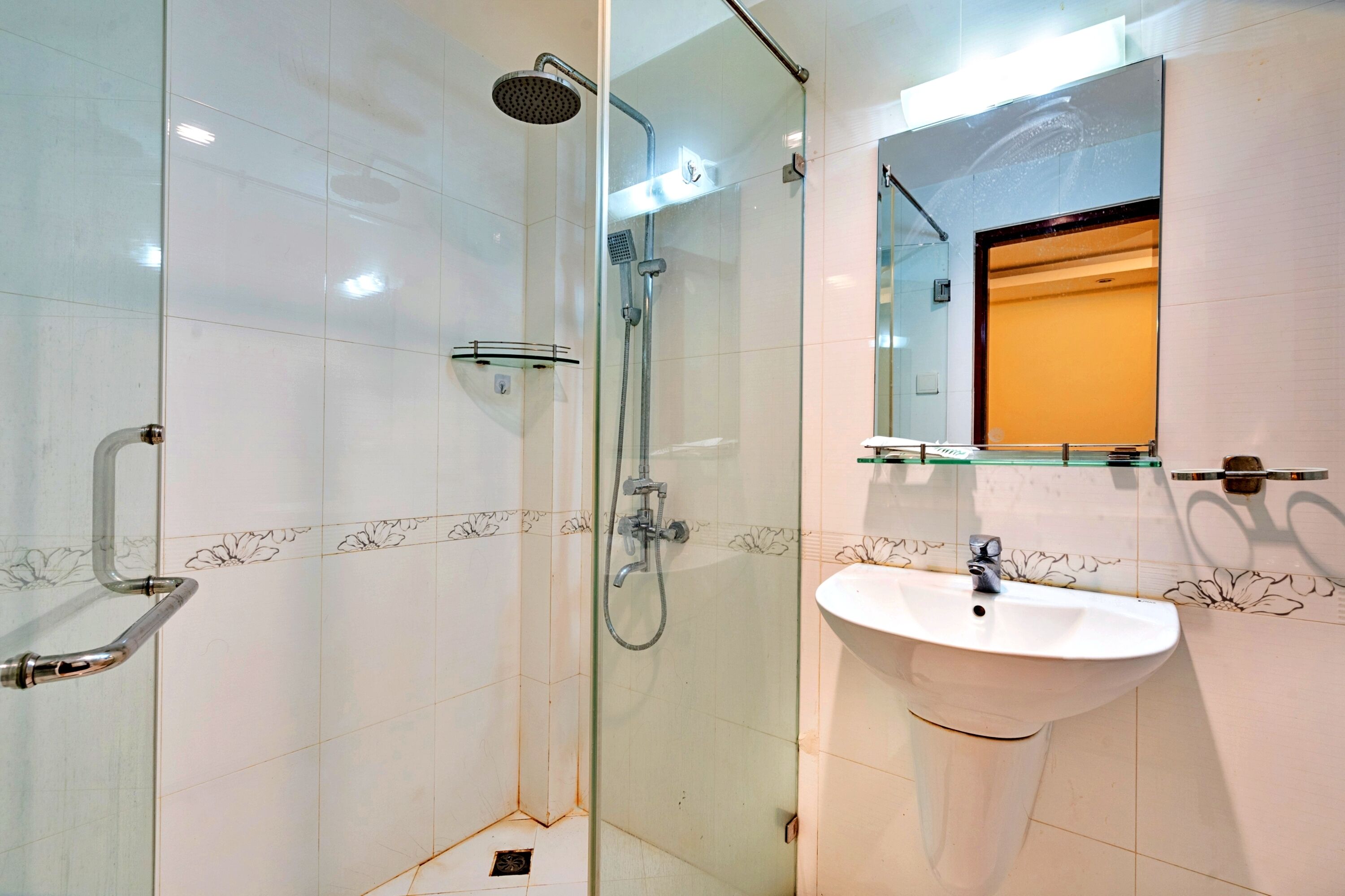 A modern bathroom with a glass-enclosed shower, a white sink, and a mirror above it.