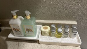 Un estante de baño con diversos artículos de aseo, como loción para manos, gel de ducha y jabón.