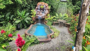 Un jardín con una fuente central rodeado de exuberante follaje y plantas en flor.