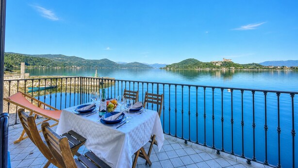 Une table dressée pour le dîner, avec vue sur un lac et des collines lointaines.