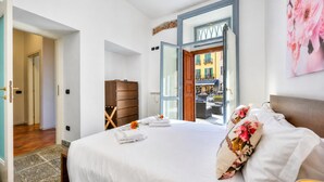 Une chambre d’hôtel avec un lit, une commode en bois, une porte donnant sur l’extérieur et un grand miroir.