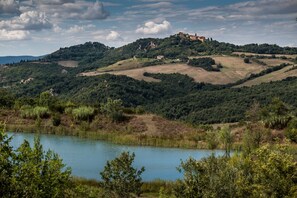 Eine malerische Landschaft mit sanften Hügeln, einem See und einem Gebäude in der Ferne auf einem Hügel.