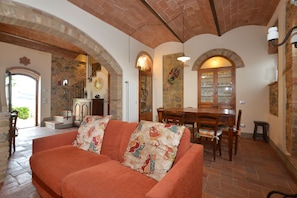 A living room with a sofa, wooden dining table, chairs, and a staircase. - Pozzovecchio, Casole d'Elsa, Italy (Casole d'Elsa)