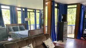Et værelse med en brun sofa, et træskab og et stort vindue med blå gardiner.
