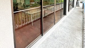 Et overdækket udeareal med glasgelænder, der giver udsigt over et naturskønt landskab.