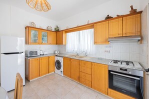 Une cuisine compacte dotée de meubles en bois, d’un four à micro-ondes, d’un lave-linge, d’un évier et d’une cuisinière.