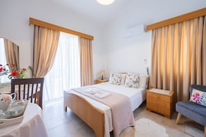 Une chambre bien éclairée, avec un lit, des tables de chevet, une chaise et une petite table sur laquelle se trouve un plateau avec du thé et des tasses.