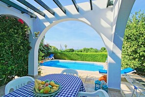 A poolside area with a checkered table, a fruit bowl, and lounge chairs. - Lemon Grove Villa Dio (Argaka)
