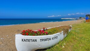 A beach with a white boat labeled "KAPETAN TRIPIMPAI KIPOS" and a clear blue sky. - Villa Majestic in Agia Marina Chrysochous (Ayia Marina Chrysochous)