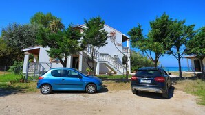 A two-story house with a balcony, a car parked in front, and a clear blue sky.