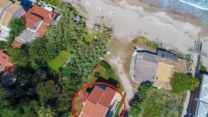 An aerial view of a coastal area with a beach, houses, and a circled building.