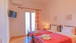 A bedroom with two beds, a TV, and a balcony view.
