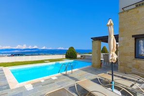 A swimming pool with a view of mountains, stone walls, and lounge chairs. - Villa Styliani in Fasli (Droushia)