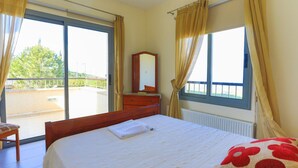 Ein Schlafzimmer mit einem großen Bett, einem Schminktisch, einem Spiegel und einem Fenster mit Vorhängen.