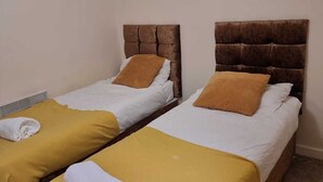 A room with two single beds, each with a brown headboard and a yellow pillow. - Central 2-bedroom Apartment, Chelmsford, Parking (Chelmsford)