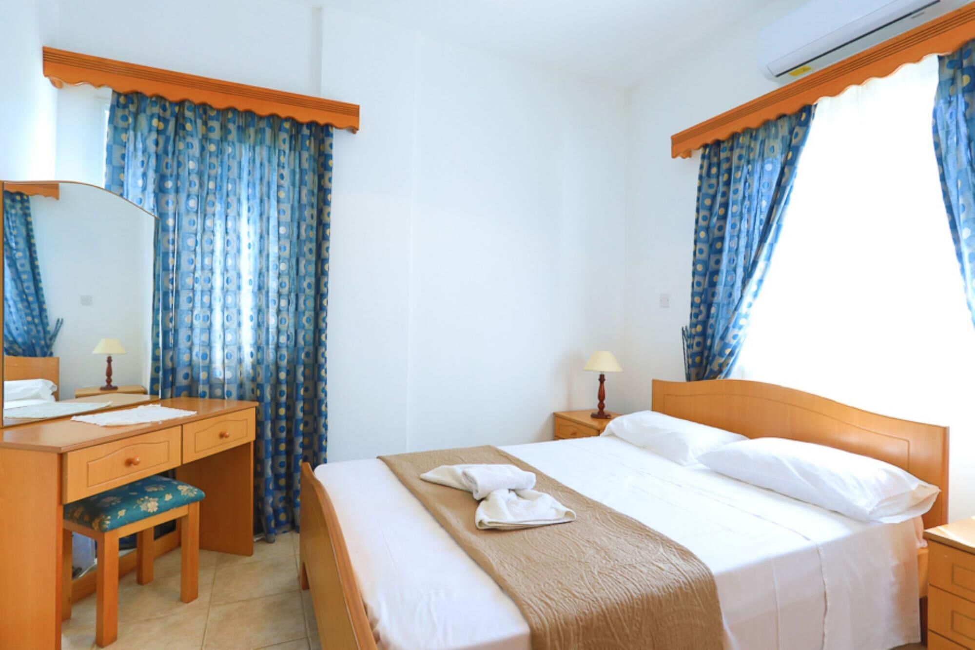 A hotel room with a bed, a desk, a chair, and a window with curtains.
