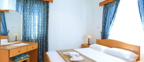 A hotel room with a bed, a desk, a chair, and a window with curtains.
