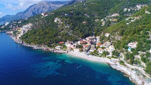 A coastal town with buildings on a hillside overlooking a clear blue sea. - Anda Studio in Katavolos (Corfu)
