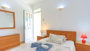 Un dormitorio con cama, mesitas de noche, un espejo y una puerta.