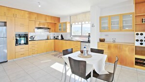 Een moderne keuken met houten kastjes, een eettafel met stoelen en uitzicht door het raam.
