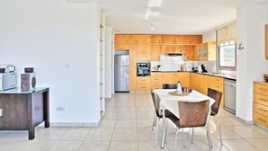 Een moderne keuken met houten kastjes, een roestvrijstalen koelkast en een eethoek met een tafel en stoelen.