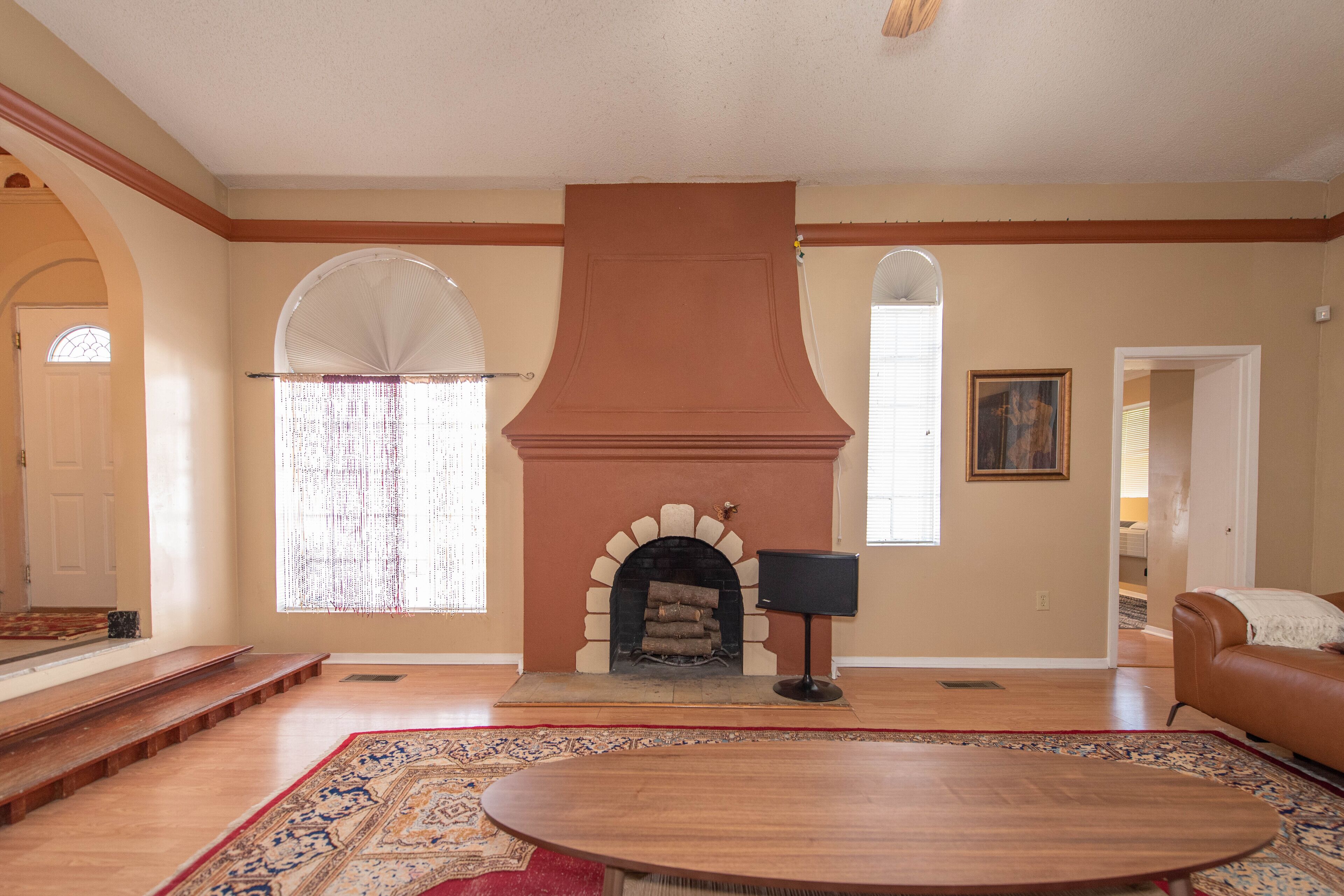 A spacious living room with a fireplace, a large rug, and a wooden coffee table.