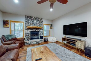 Cozy living room with a fireplace, leather sofas, and a large flat-screen TV.