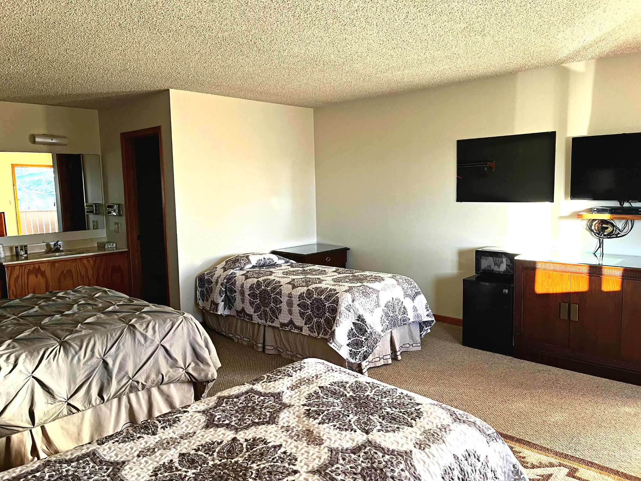 Une chambre d’hôtel avec deux lits, une télévision, un bureau et un miroir.