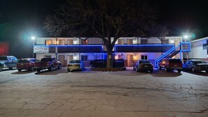 A motel with a two-story building, a parking lot, and a tree in front. - Furnas County Lodging (Beaver City)