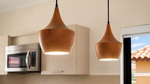 Zwei Pendelleuchten mit Holzoptik in einer Küche mit Mikrowelle und Schränken.