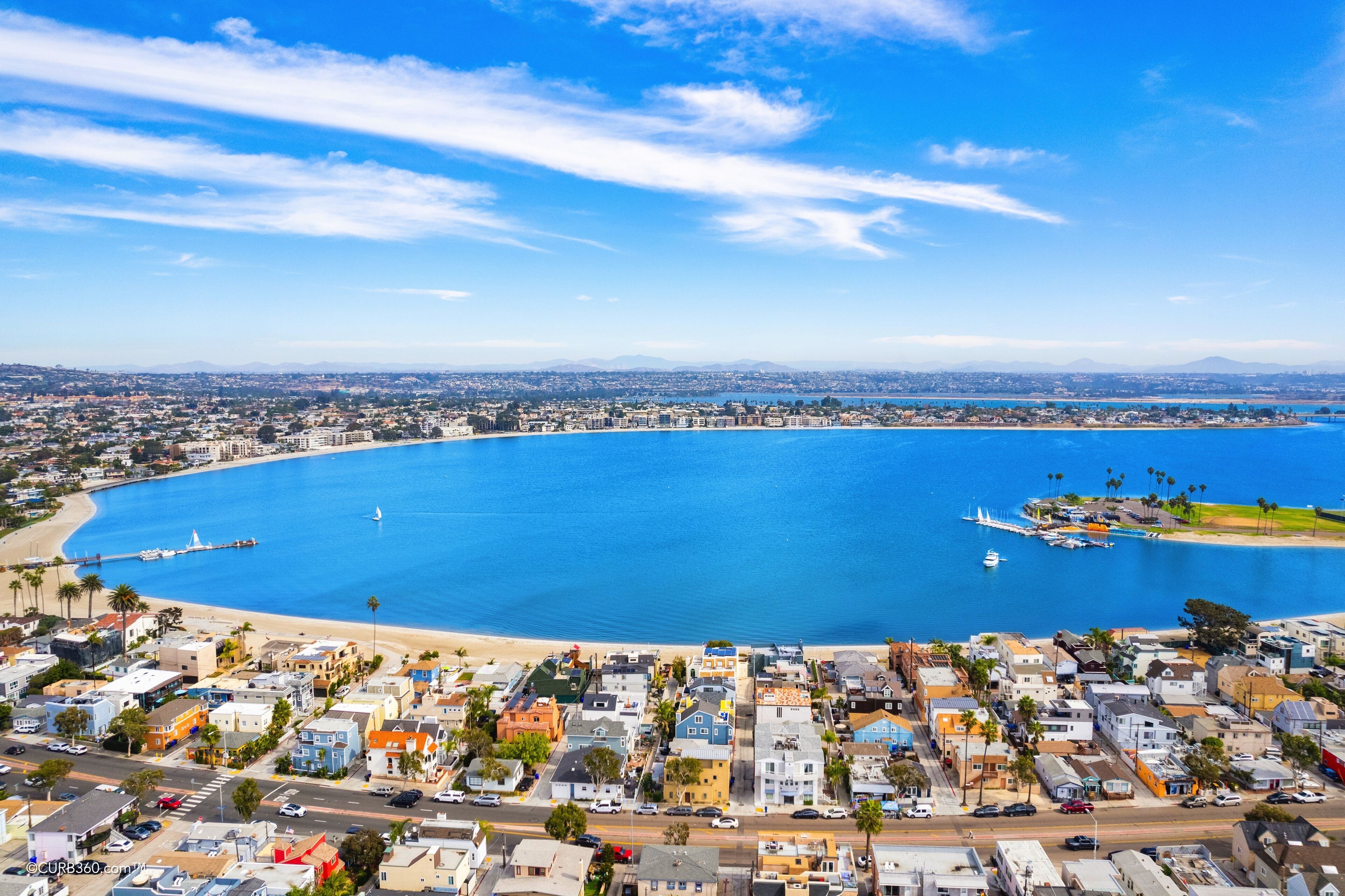 An aerial view of a coastal city with a large bay, residential buildings, and a pier.