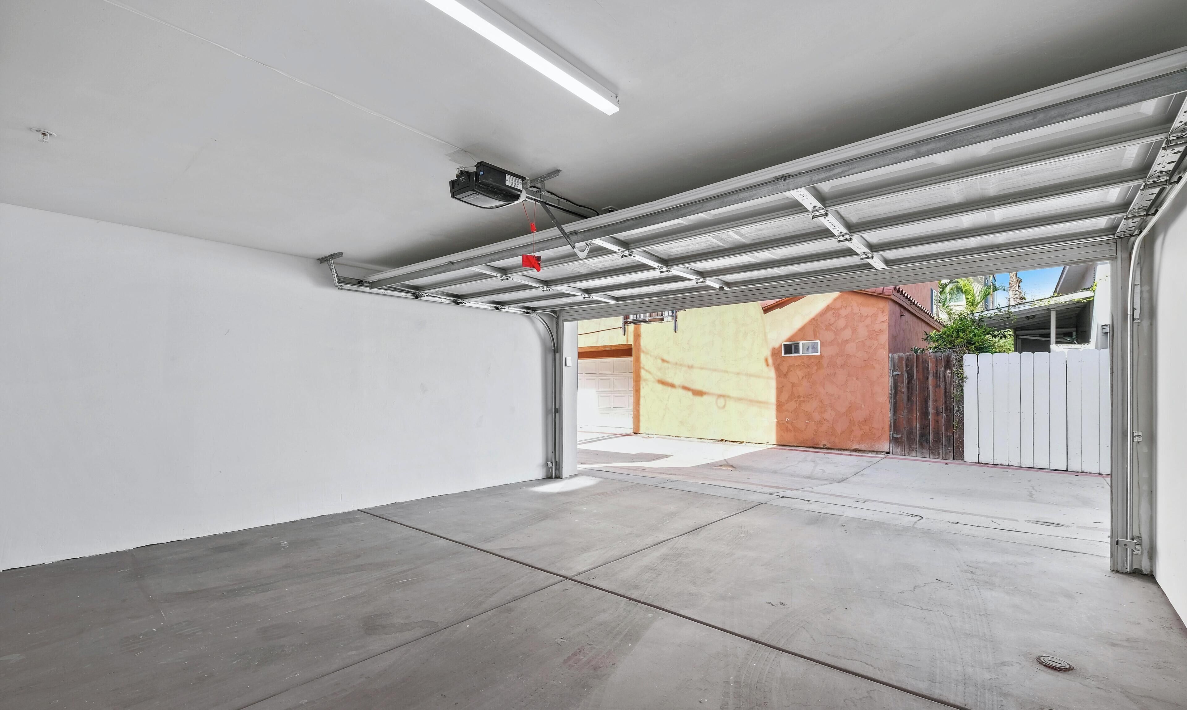 Un garage con pavimento in cemento, parete bianca e porta metallica.
