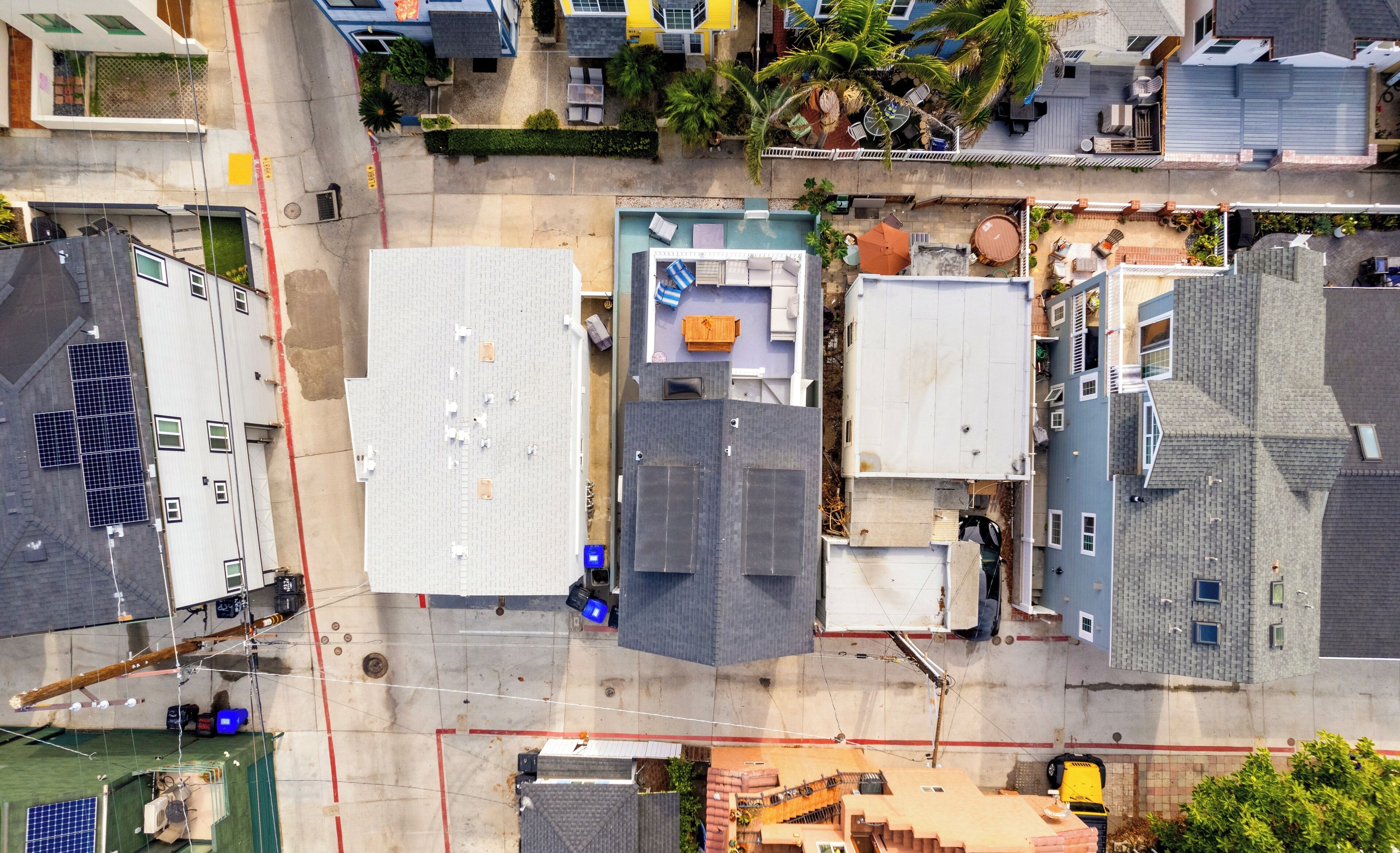 An aerial view of a residential area with multiple buildings, including a house with a rooftop pool and a garage.